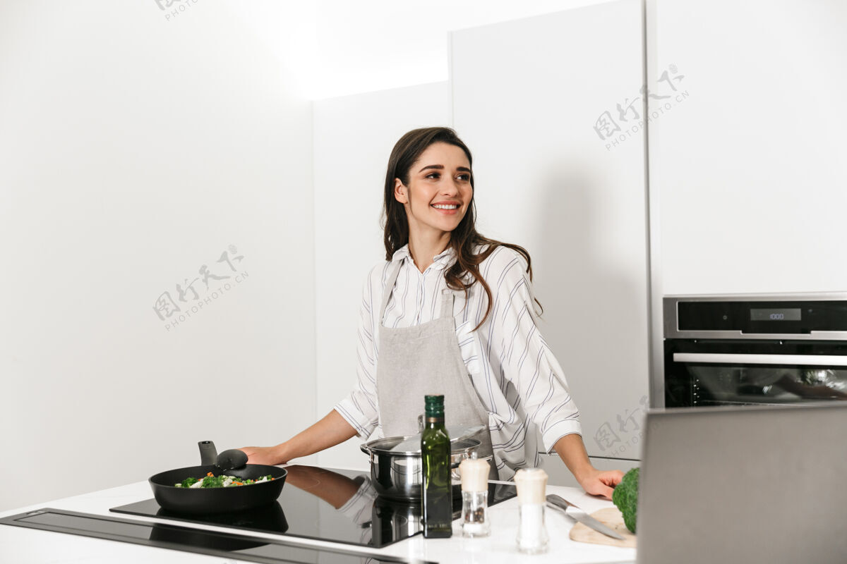 家庭主妇美丽的年轻女子在厨房做健康的晚餐早餐白种人围裙