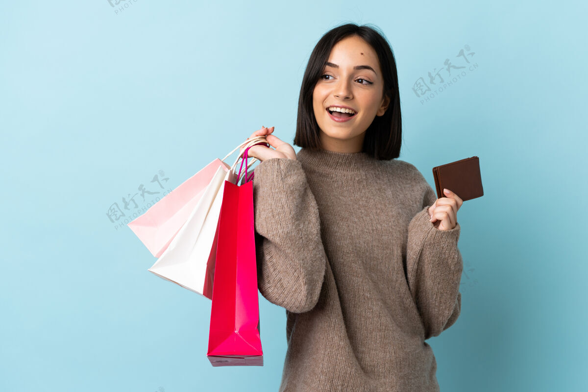 购物者带着购物袋的女孩在与世隔绝的背景下年轻钱商业