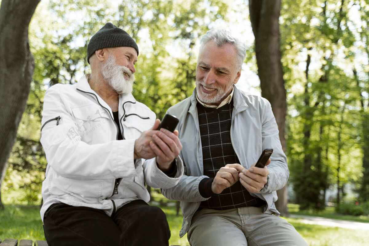 老年人带着智能手机的中枪笑脸老人户外生活方式男人