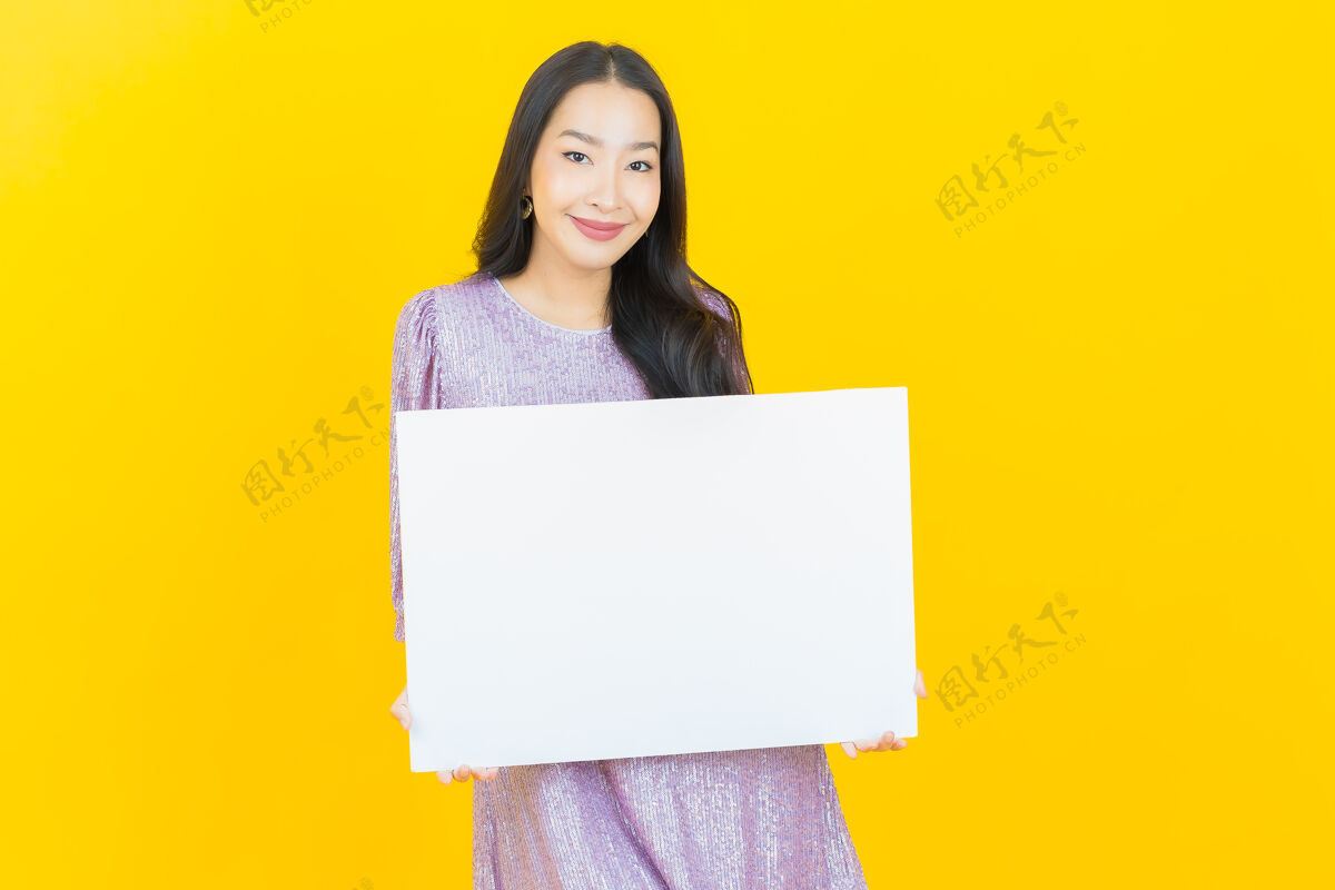 表一个年轻的亚洲女人拿着黄色的白色广告牌女性中国人标语牌