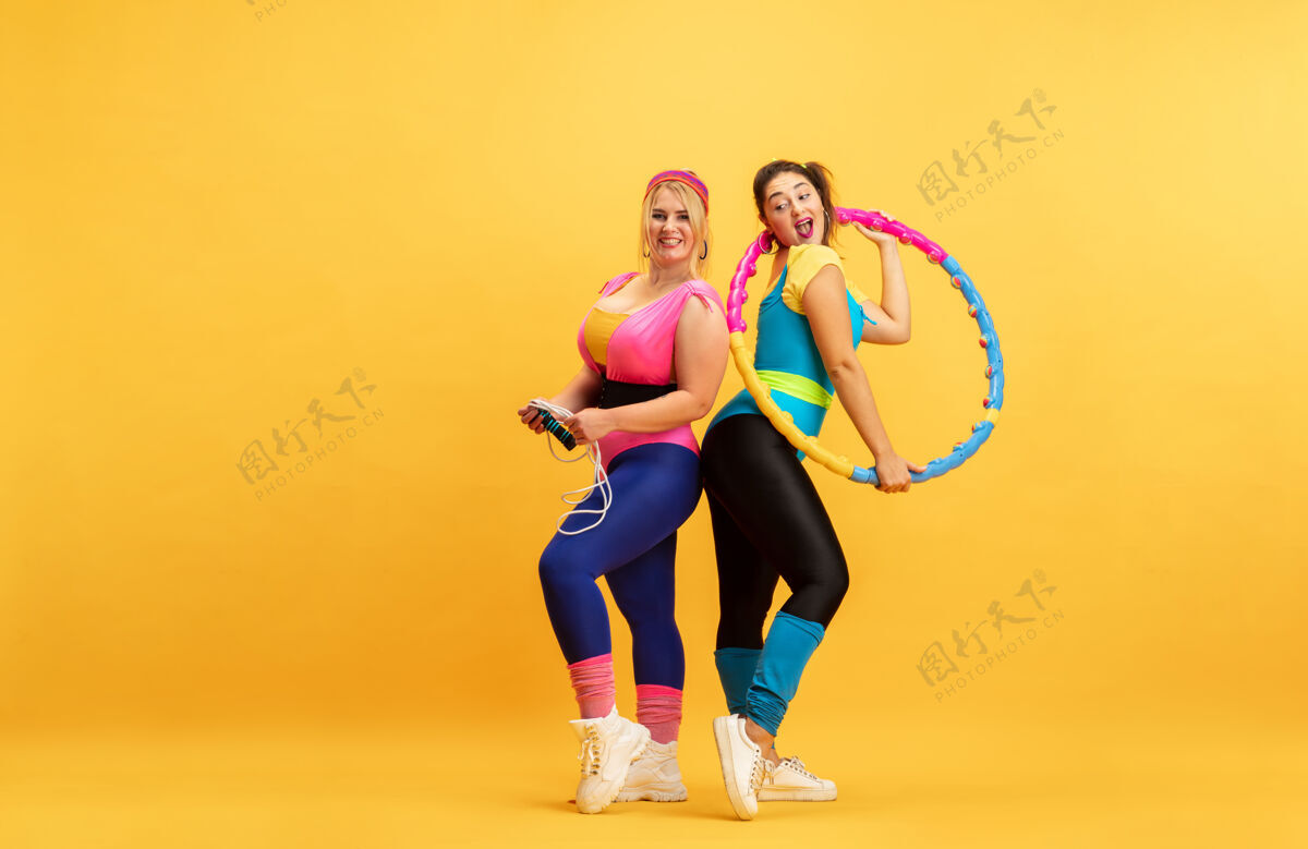 人年轻女子在黄墙上训练力量女人锻炼
