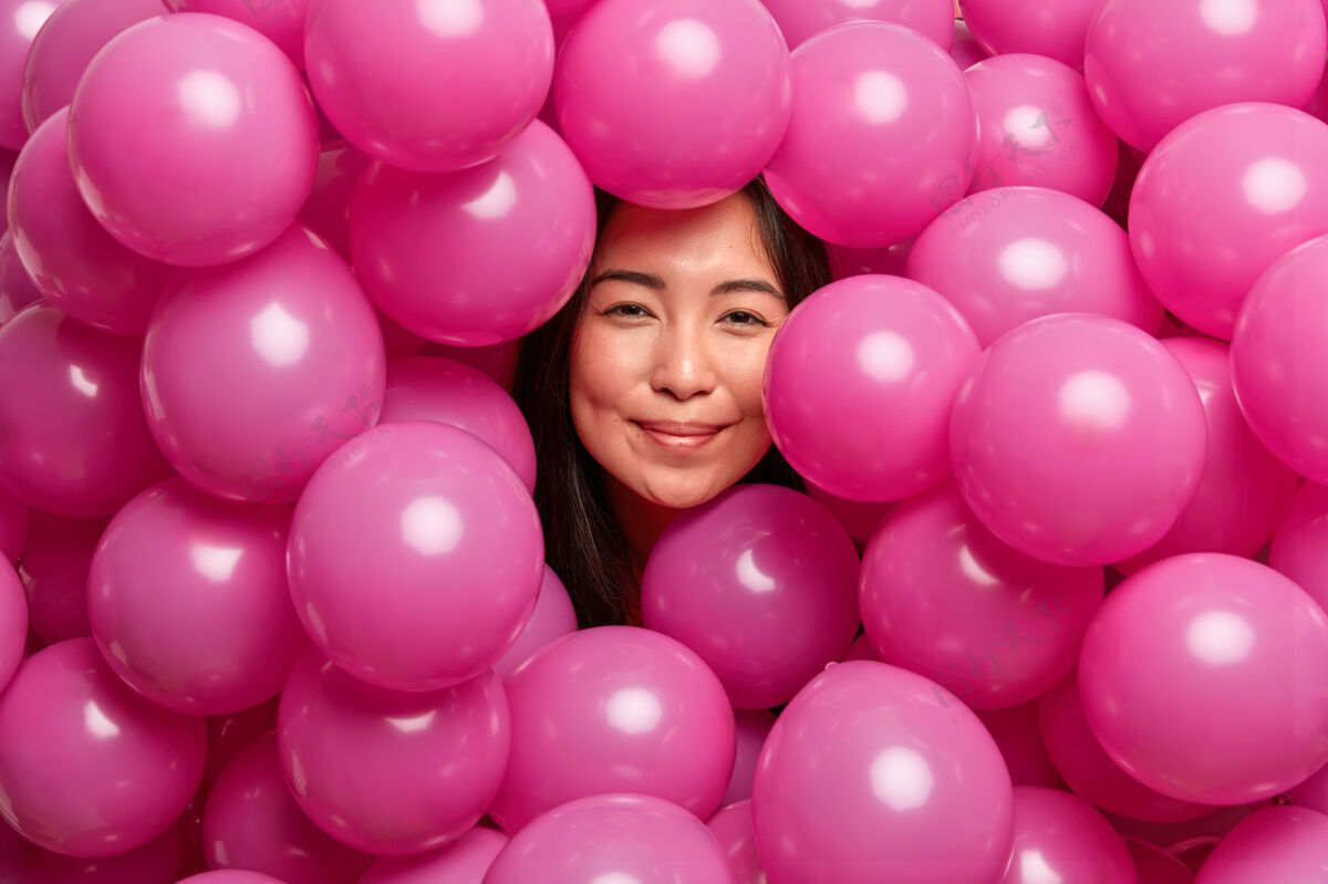 乐观女人在生日派对上被粉红色的充气气球团团围住了高兴节日姿势