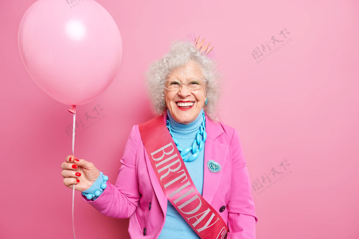 微笑一位头发卷曲 满脸皱纹的老年妇女手持充气气球庆祝生日室内卷曲高兴