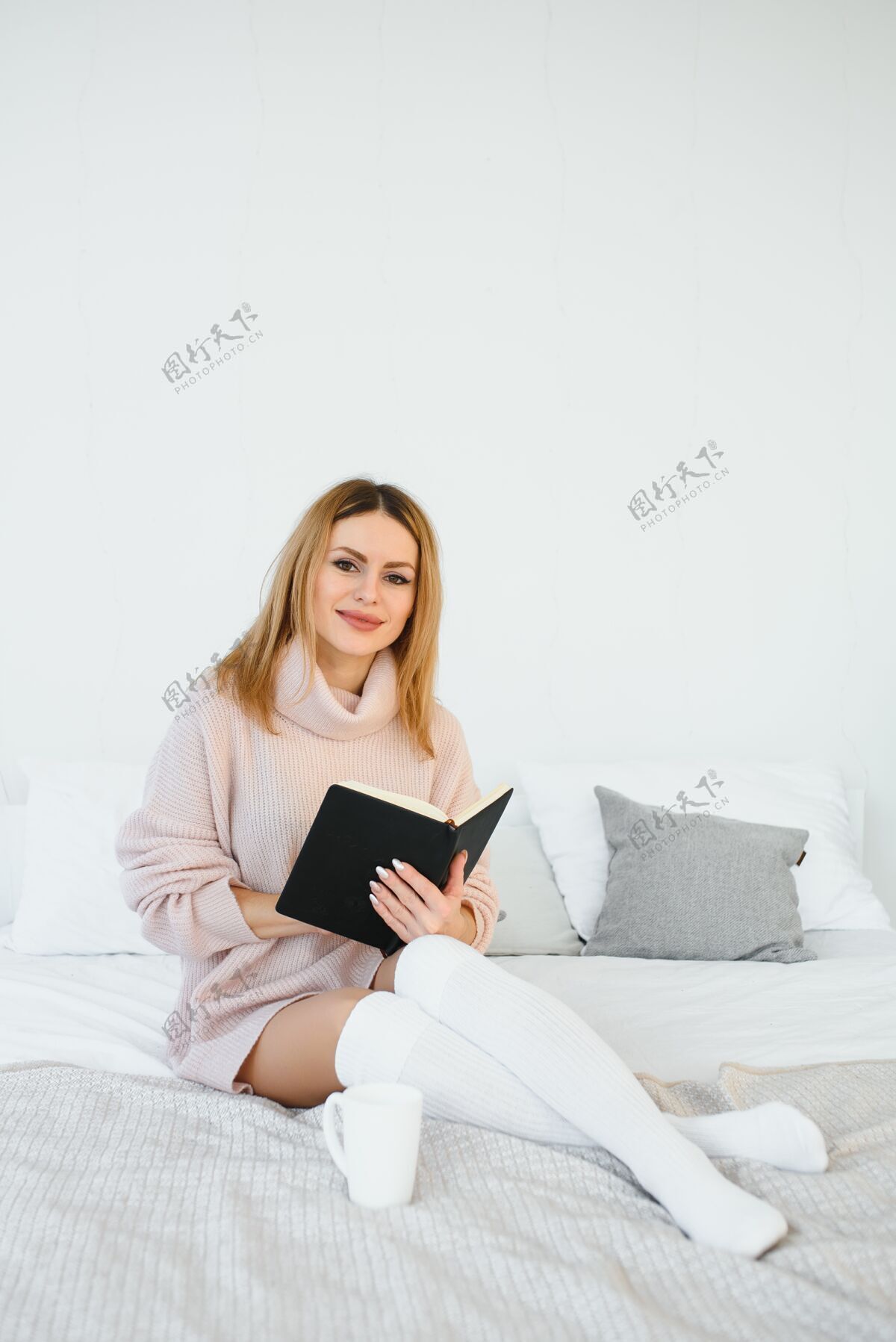灯一个女人在看书 坐在椅子上微笑bed.the她旁边桌子上的闹钟放松阅读漂亮