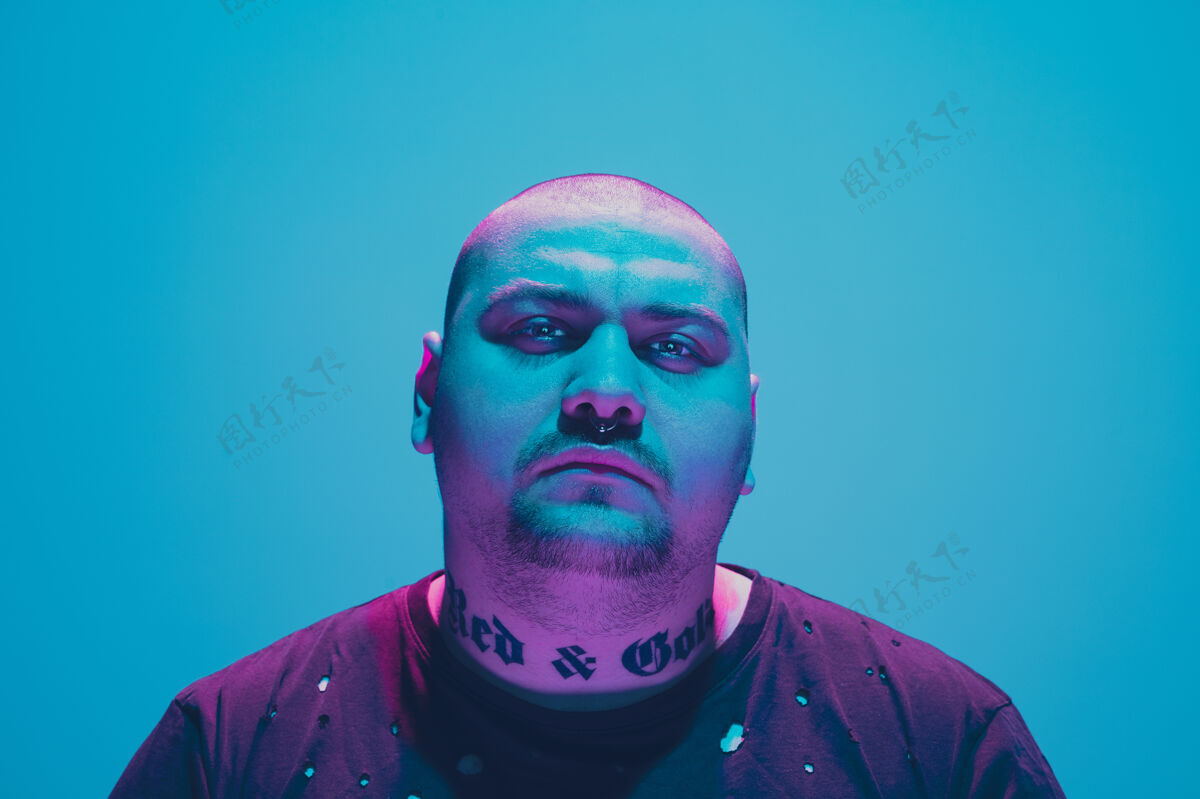 情感一个时髦男人的肖像 蓝色背景上有五颜六色的霓虹灯男人室内说唱歌手
