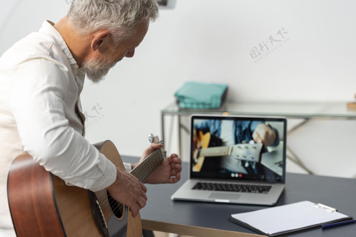 老年人在家学习吉他课笔记本电脑的高级男子养老金学习水平