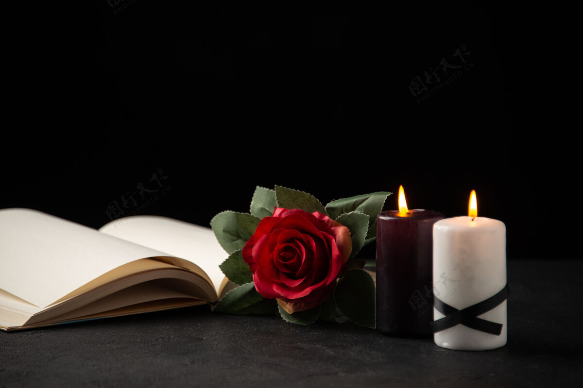 花打开的书与蜡烛和黑色玫瑰的正面视图蜡烛葬礼打蜡