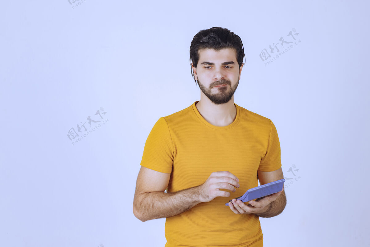 男性穿黄衬衫的人在计算器上计算着什么人类姿势年轻人