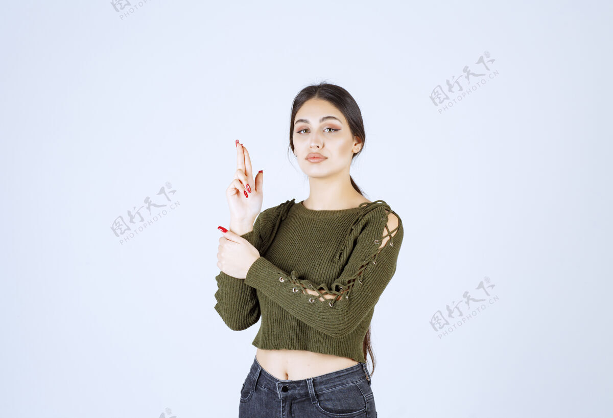 女人一个严肃的年轻女模特用手和手指练习手枪的照片肖像严肃手指