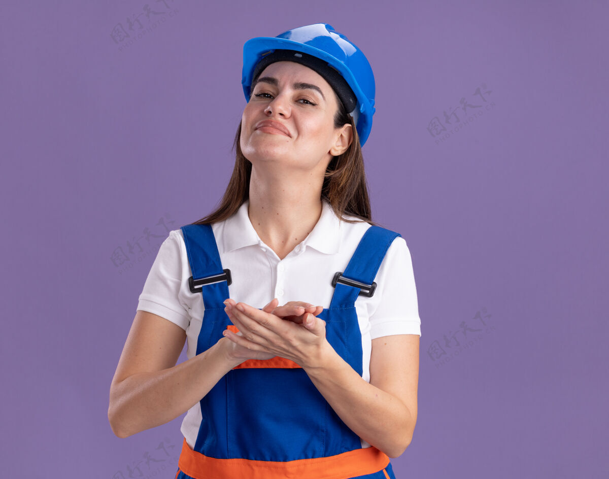 手自信的穿着制服的年轻建筑女手牵手孤立在紫色的墙上自信握着建设者