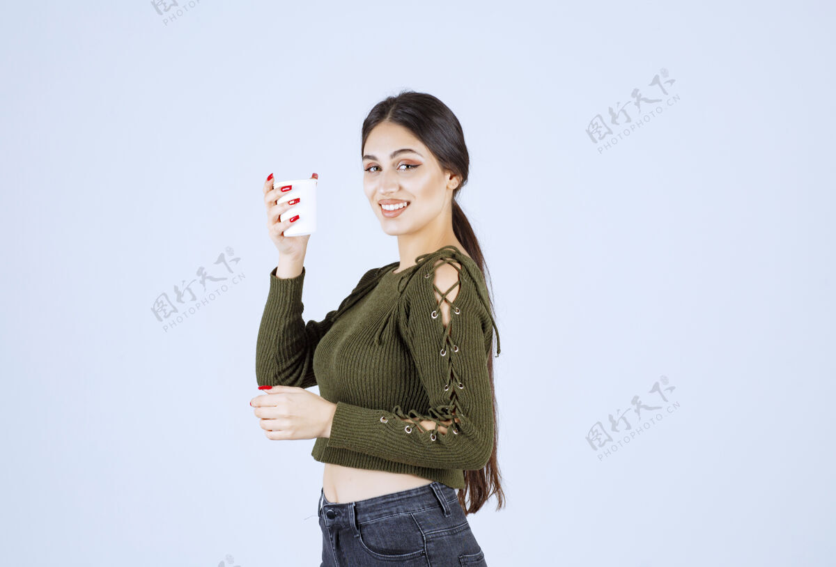 杯子年轻的黑发女人在白色背景上快乐地摆着塑料杯的姿势持有成人女孩