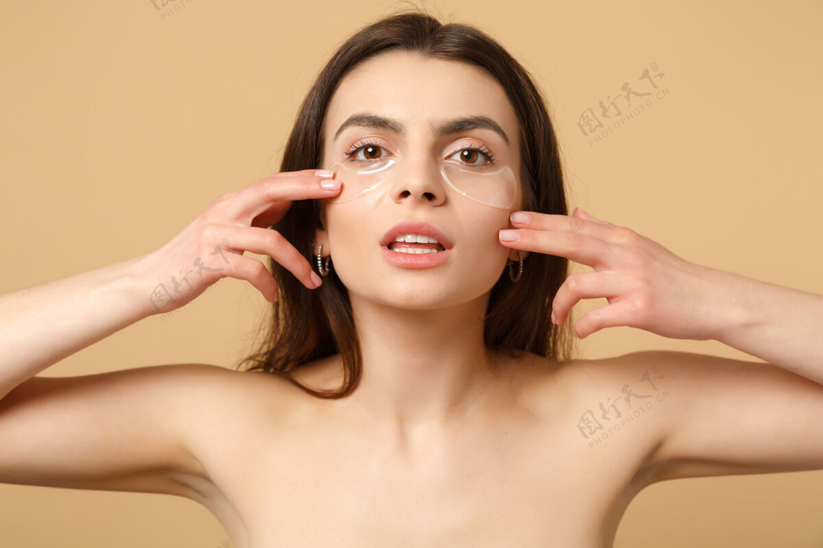 补丁近距离拍摄完美皮肤的半裸女人 在米色粉彩墙上隔离眼睛下的裸妆贴片光滑纯净女性