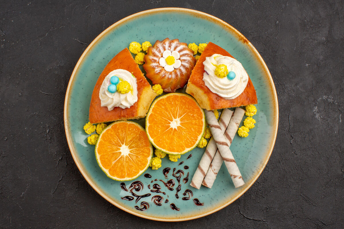 可食用的水果顶视图美味的蛋糕片与烟斗饼干和切片橘子在黑暗的背景水果柑橘蛋糕派饼干甜茶观点柑橘新鲜