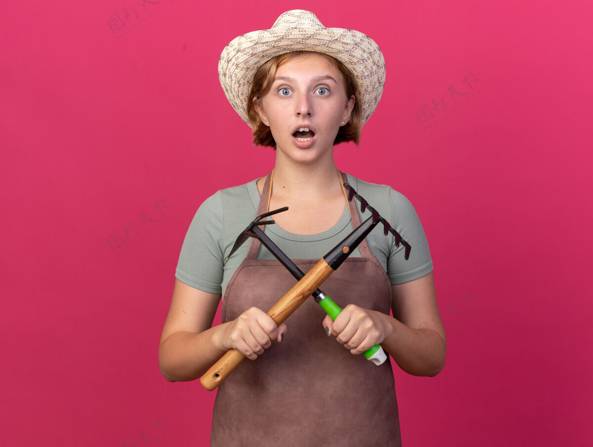 帽子震惊年轻的斯拉夫女园丁戴着园艺帽拿着耙子和锄头耙子女性斯拉夫耙子