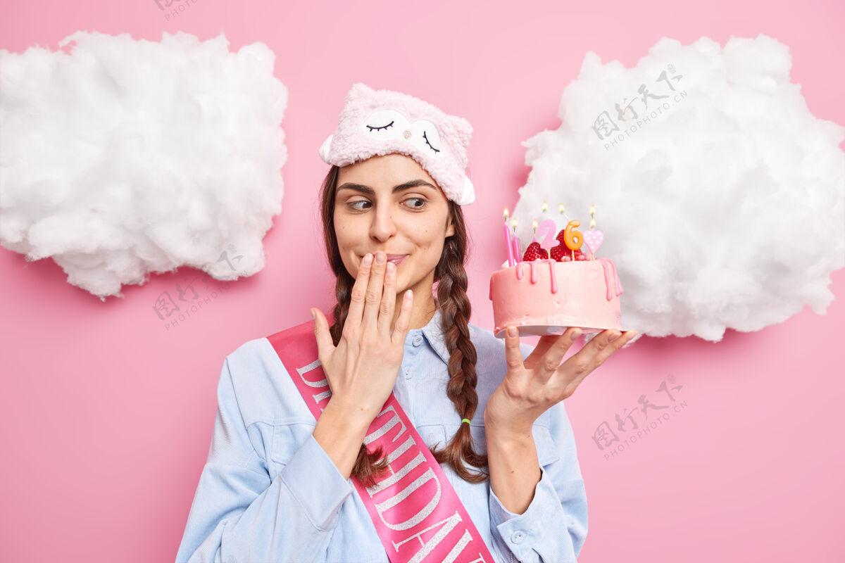 充气女人带着诱惑看着美味的蛋糕 嘴里等着客人 生日派对上戴着睡眠面具 衬衫上隔离着粉色蛋糕活动罗西
