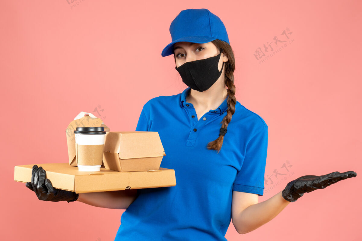 面具半身镜头满意的信使女孩戴着医用口罩和手套举行粉彩桃背景命令工人工作秩序