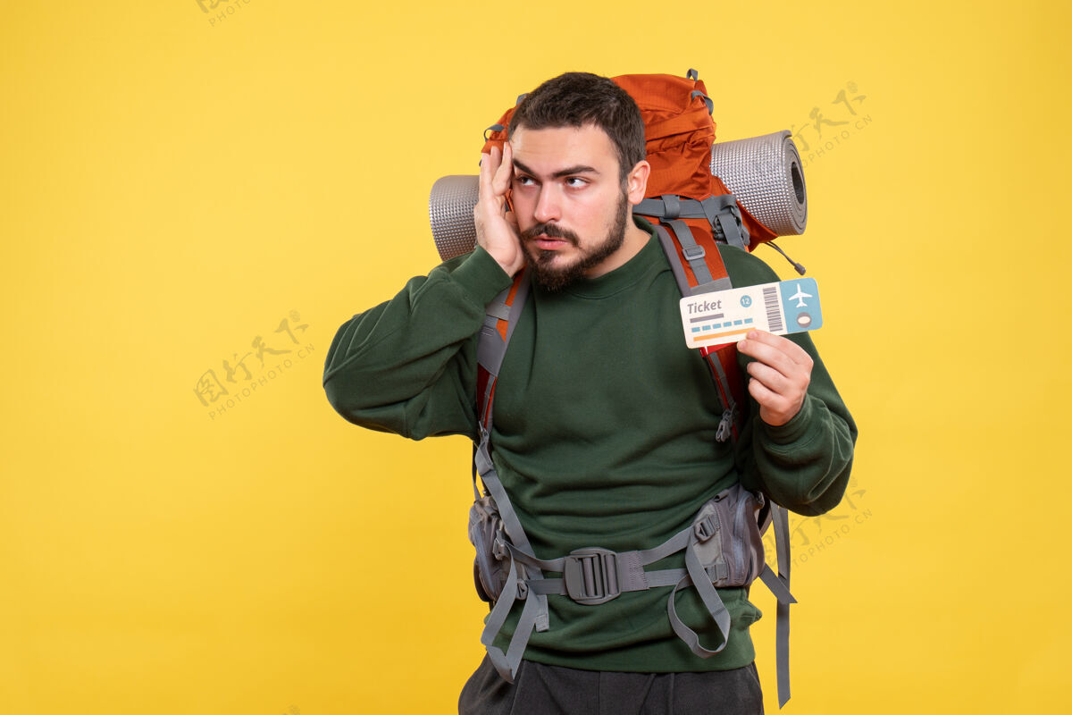 套装黄色背景上背着背包拿着票的旅行男人的正面视图手持正面背包