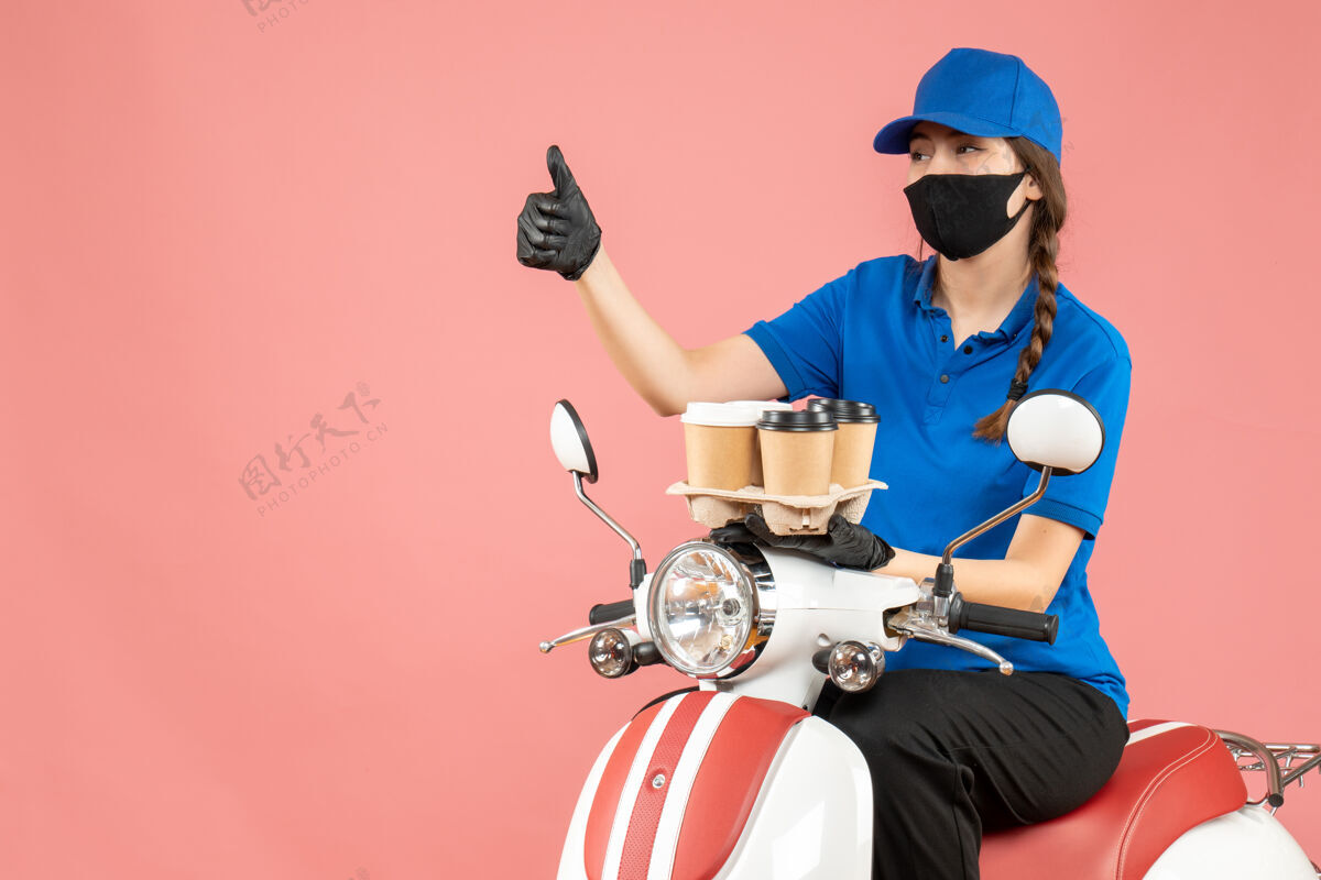 面具戴着医用面罩和手套的女送货员坐在滑板车上 手持指示灯 背景是粉色的桃色男性坐前面