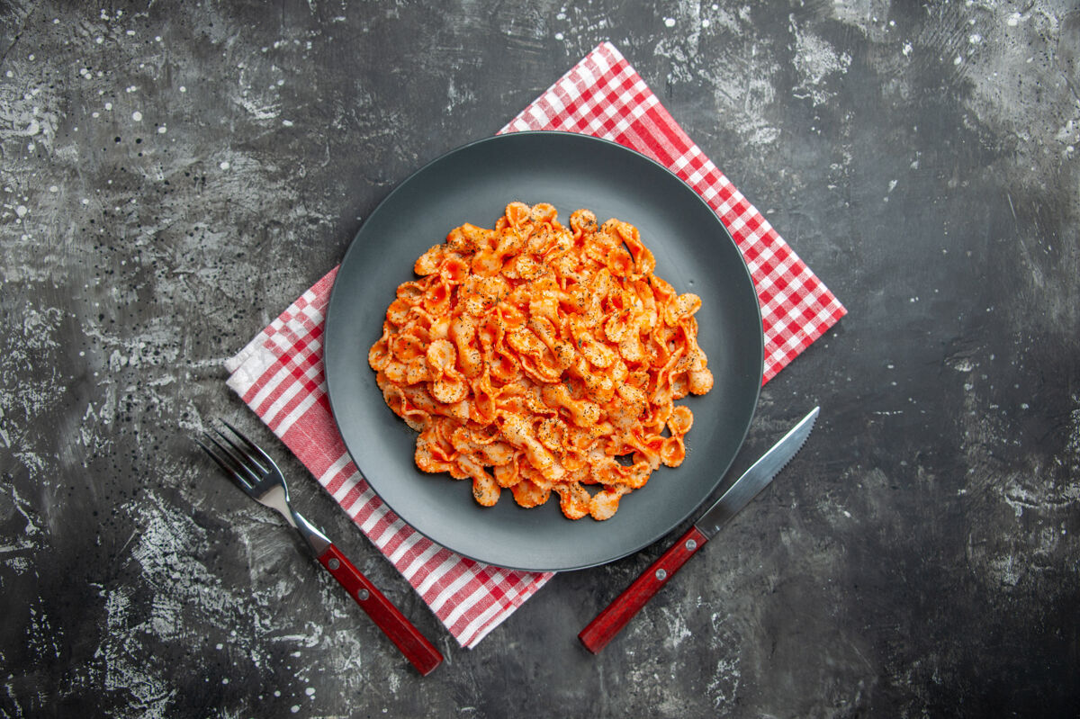 餐具上图：美味的面食放在一个黑色的盘子里 用红色的条布做晚餐食物午餐晚餐