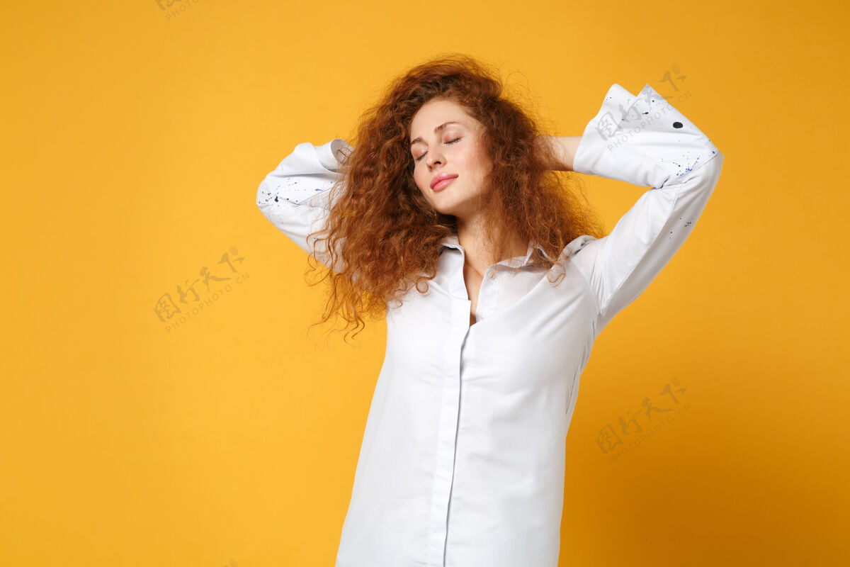 冷静放松的年轻红发女女孩在休闲白衬衫摆出孤立的黄橙色墙上女人脸显示
