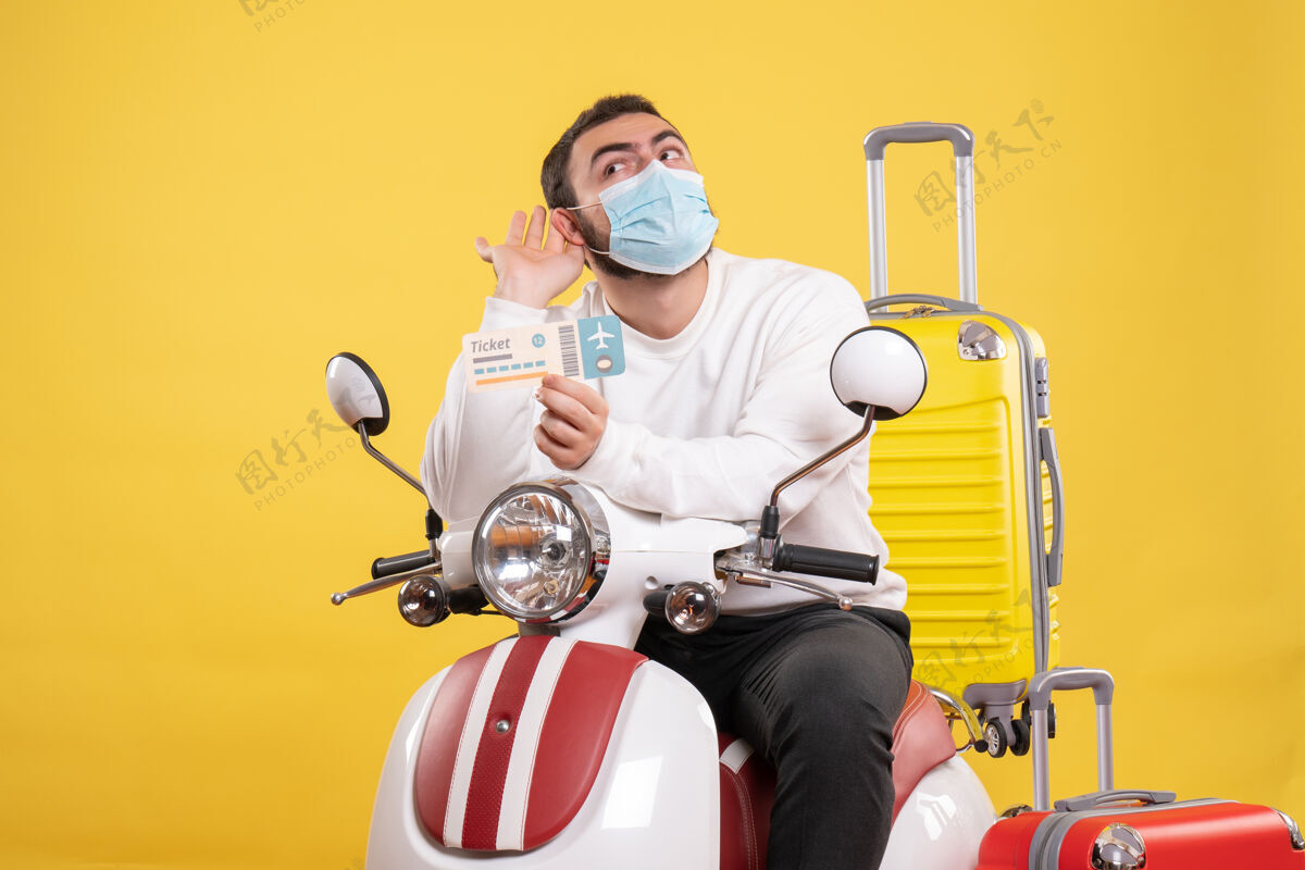 年轻人旅行概念的俯视图 戴着医用面罩的年轻人坐在摩托车上 带着黄色的手提箱 拿着车票听着最后的闲话摩托车视图人