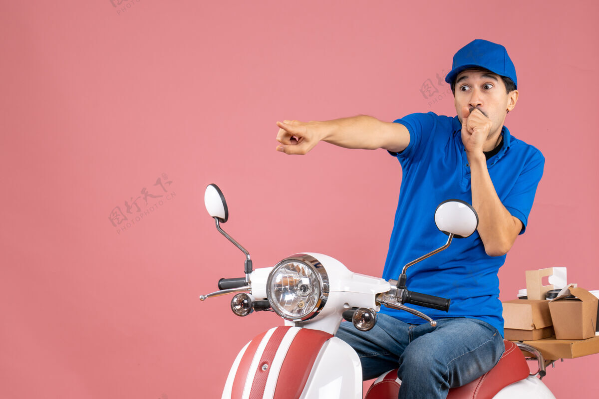 帽子俯视图惊讶的快递员戴着帽子坐在滑板车上传递订单指向粉彩桃人球员人