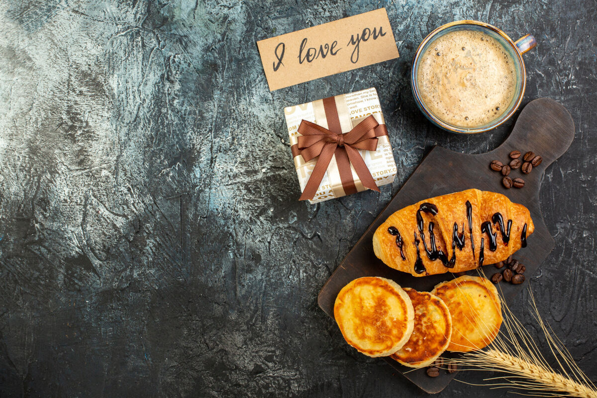 煎饼俯瞰一杯咖啡和新鲜美味的早餐美丽的礼品盒煎饼croissant在黑暗的背景坚果顶部咖啡