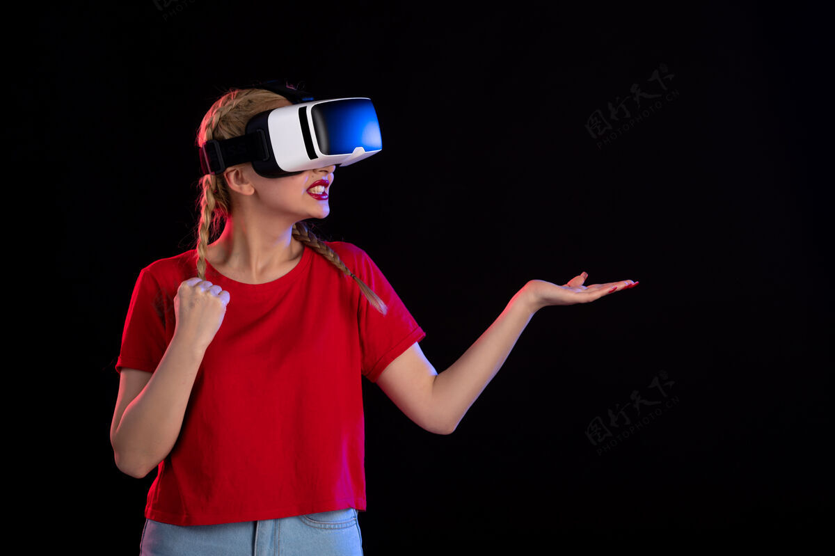 人物年轻女性在黑暗的墙上玩虚拟现实的正面图正面视觉黑暗