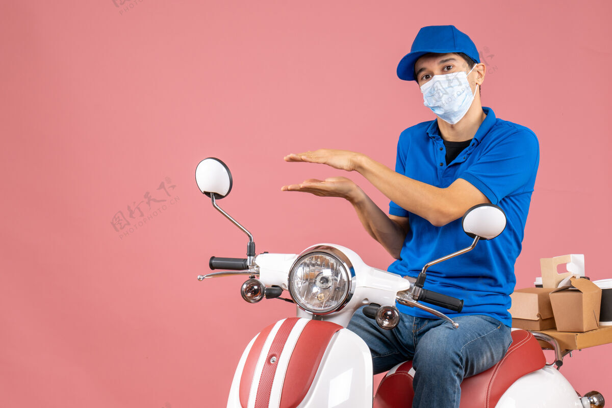 快递员顶视图的快递员戴着医疗面具 戴着帽子坐在滑板车上解释一些粉彩桃背景医疗解释摩托车