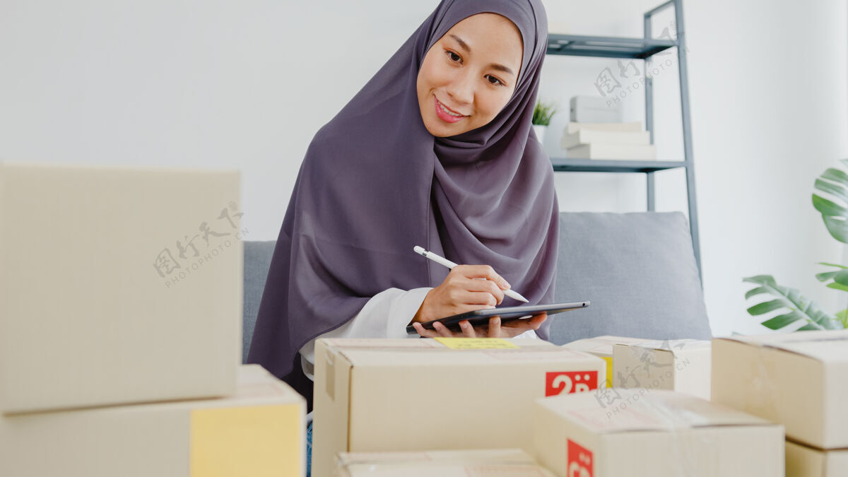 包装年轻的女商人检查产品采购订单的库存和保存到平板电脑工作在家办公办公室印尼语计算机