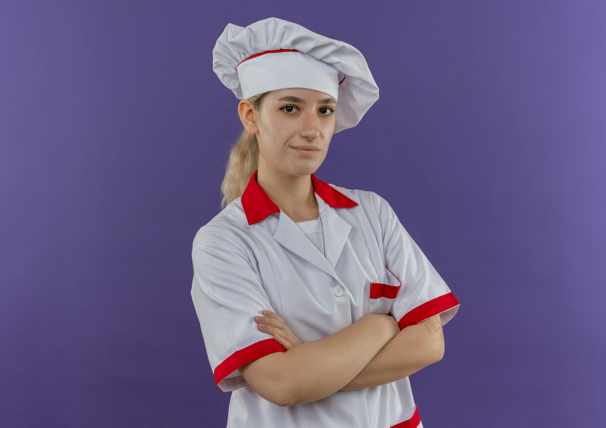 厨师自信的年轻漂亮厨师身着厨师制服 站在紫色墙壁上 封闭的姿势看起来很孤立 有复制空间年轻封闭烹饪