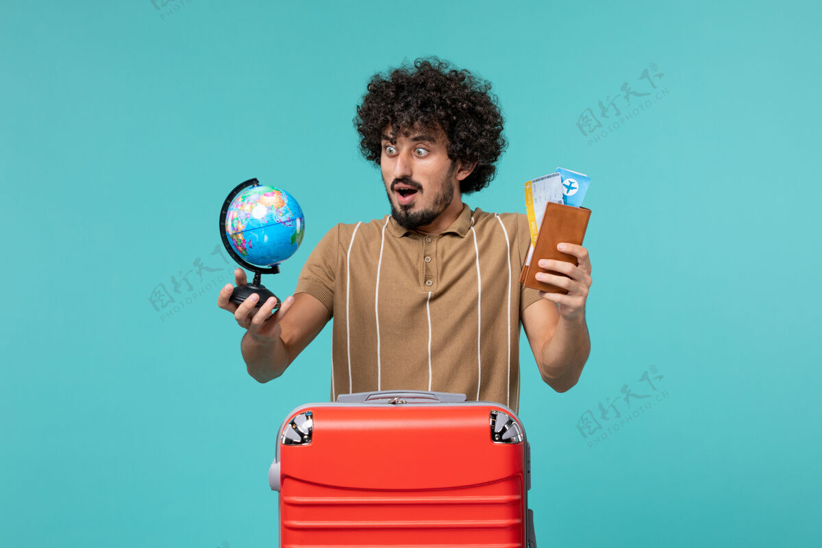 旅行度假的人拿着小地球仪和蓝色的机票肖像航行人
