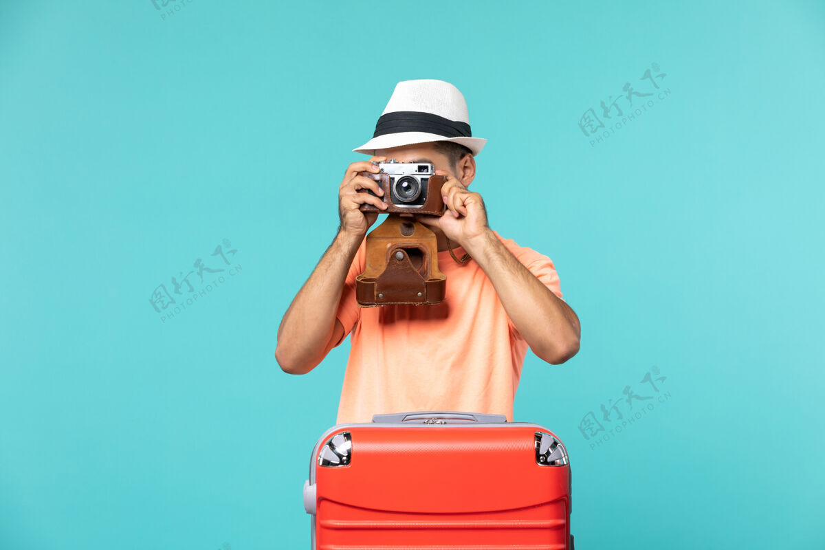 旅行带着红色手提箱的度假男人用蓝色的相机拍照镜头拍摄包