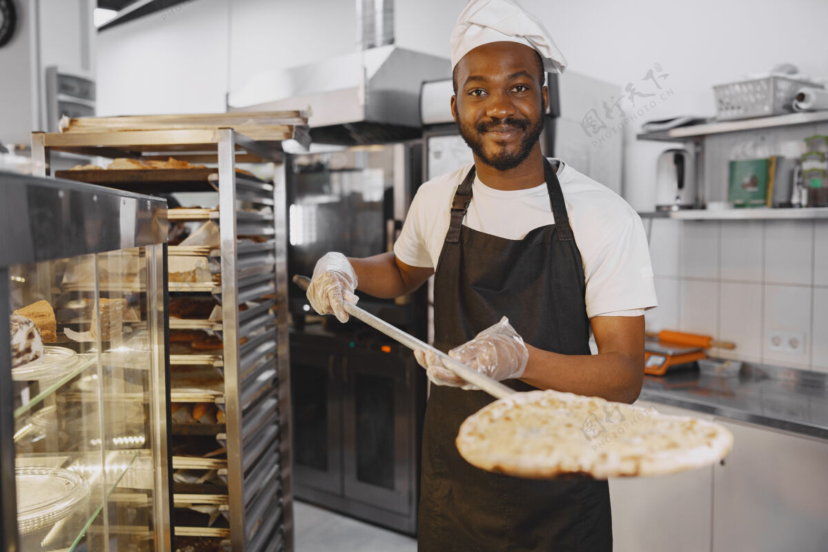 服务帅哥披萨在比萨店的厨房里做披萨非洲裔美国人笑酒吧番茄