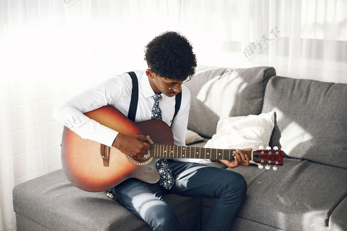 课Hoobies概念穿着紧身衣的印度年轻人坐在客厅里音乐家在弹吉他学习休息时间