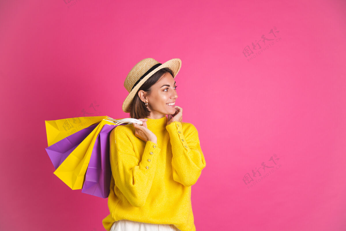 购物者美丽的女人穿着鲜艳的黄色毛衣 戴着草帽 手里拿着粉色购物袋 快乐兴奋 快乐孤立的文字空间折扣兴奋时尚
