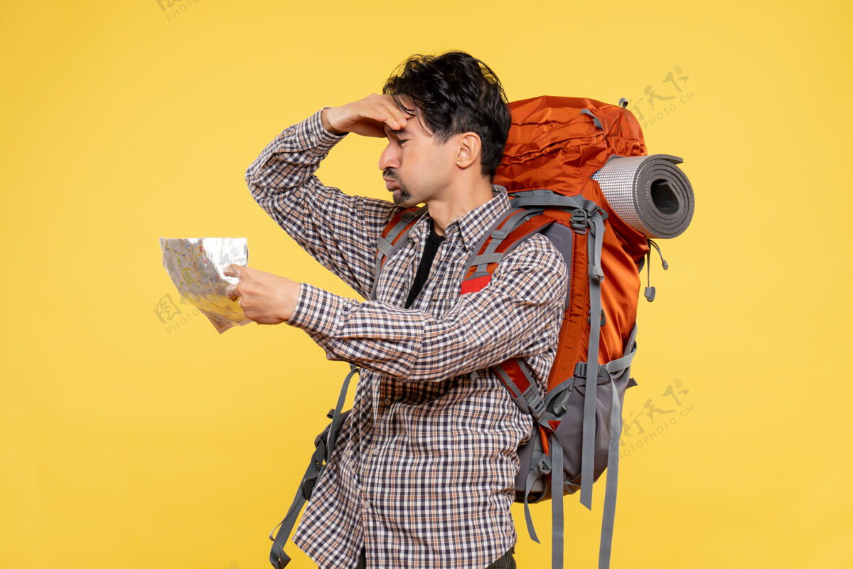 音乐家正面图年轻男性带着背包徒步旅行黄色背景上的观察地图公司旅行自然森林色彩空气公司背包人