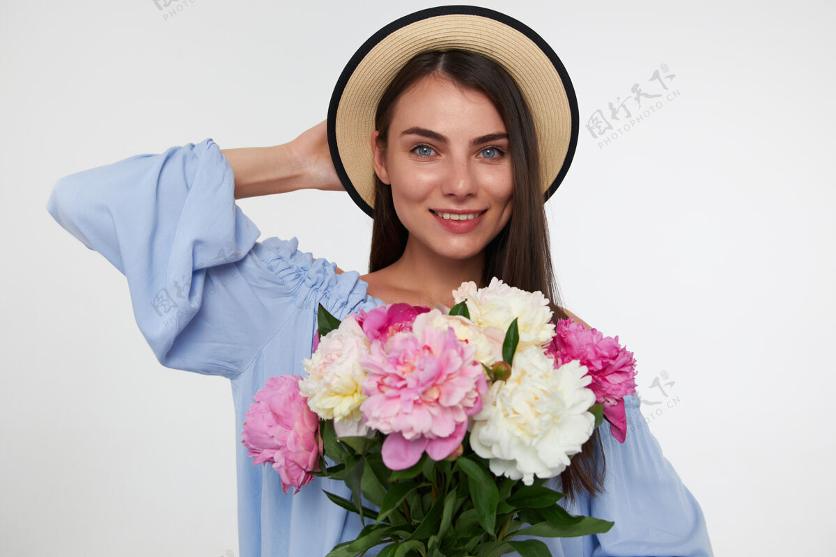 肖像一个快乐的女人 深色的长发 戴着帽子 穿着蓝色的裙子 手里拿着一束花 抚摸着她的头年轻女性女士