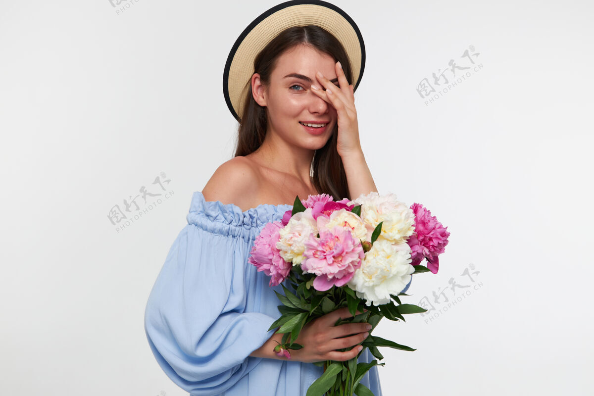 感觉少女微笑着 一头深色长发 戴着帽子 穿着蓝色漂亮的裙子 手里拿着一束花 用手指看着完美模特深褐色