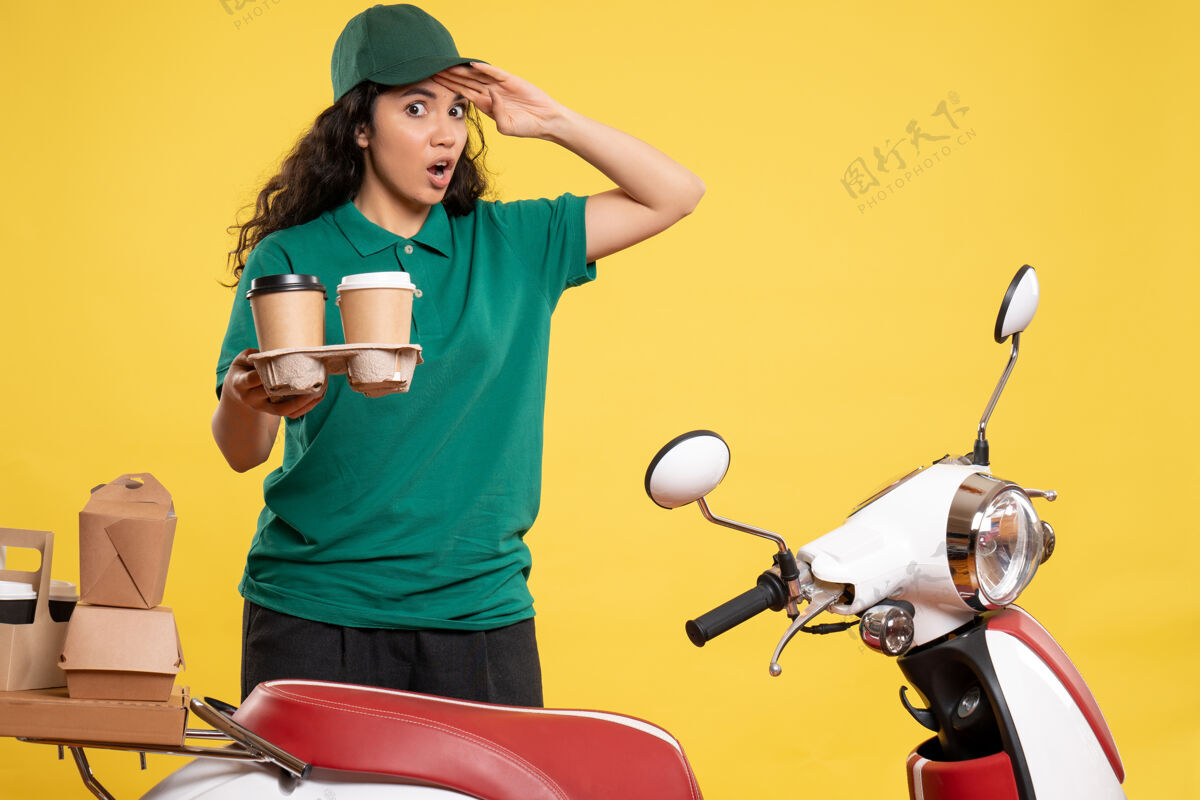 高尔夫球手正面是身着绿色制服的女快递员 背景是咖啡 背景是黄色的服务人员工作递送工作食物的女性颜色工人工作食物