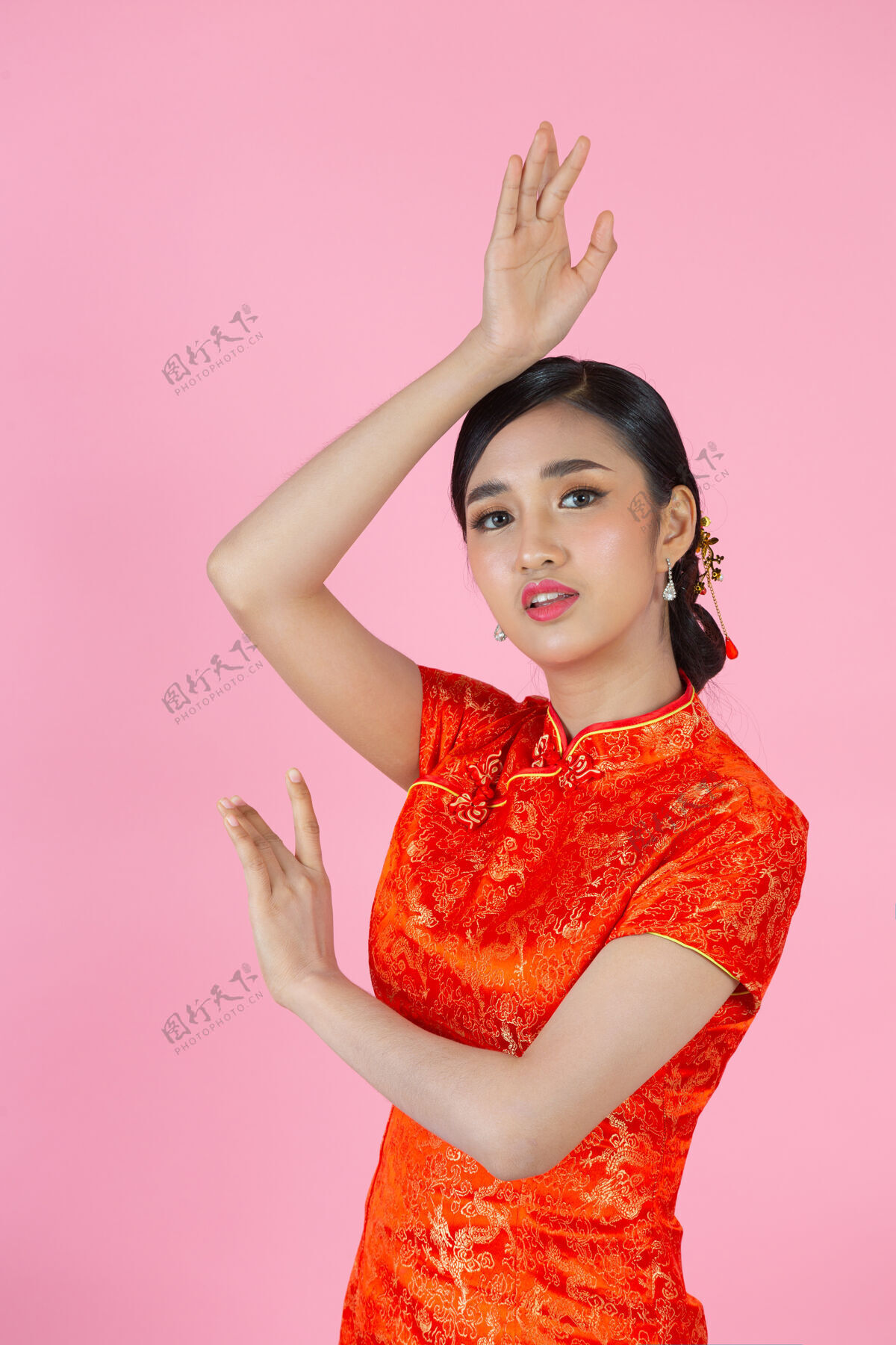 红色美丽的亚洲女人快乐的微笑 在中国新年的粉红色背景上向你展示一些东西东方人亚洲人女性