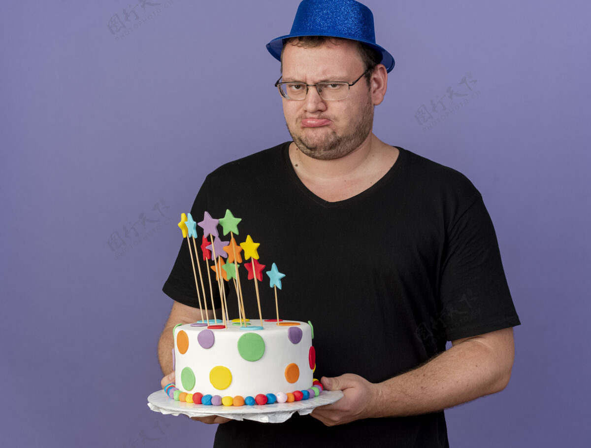穿一个戴着眼镜 戴着蓝色派对帽 拿着生日蛋糕的未获释的成年斯拉夫男子复制聚会帽子