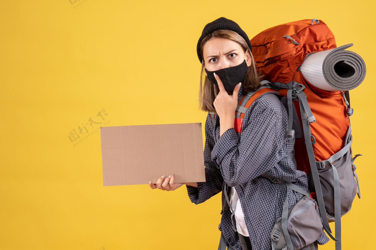 黑人带着黑色面具 背着硬纸板的背包的年轻女旅行者成人公司人