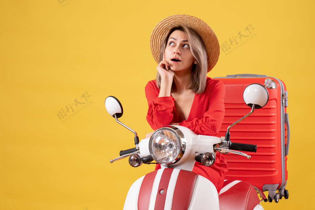 红色体贴的漂亮女孩 骑着轻便摩托车 带着红色手提箱手提箱轮廓成人