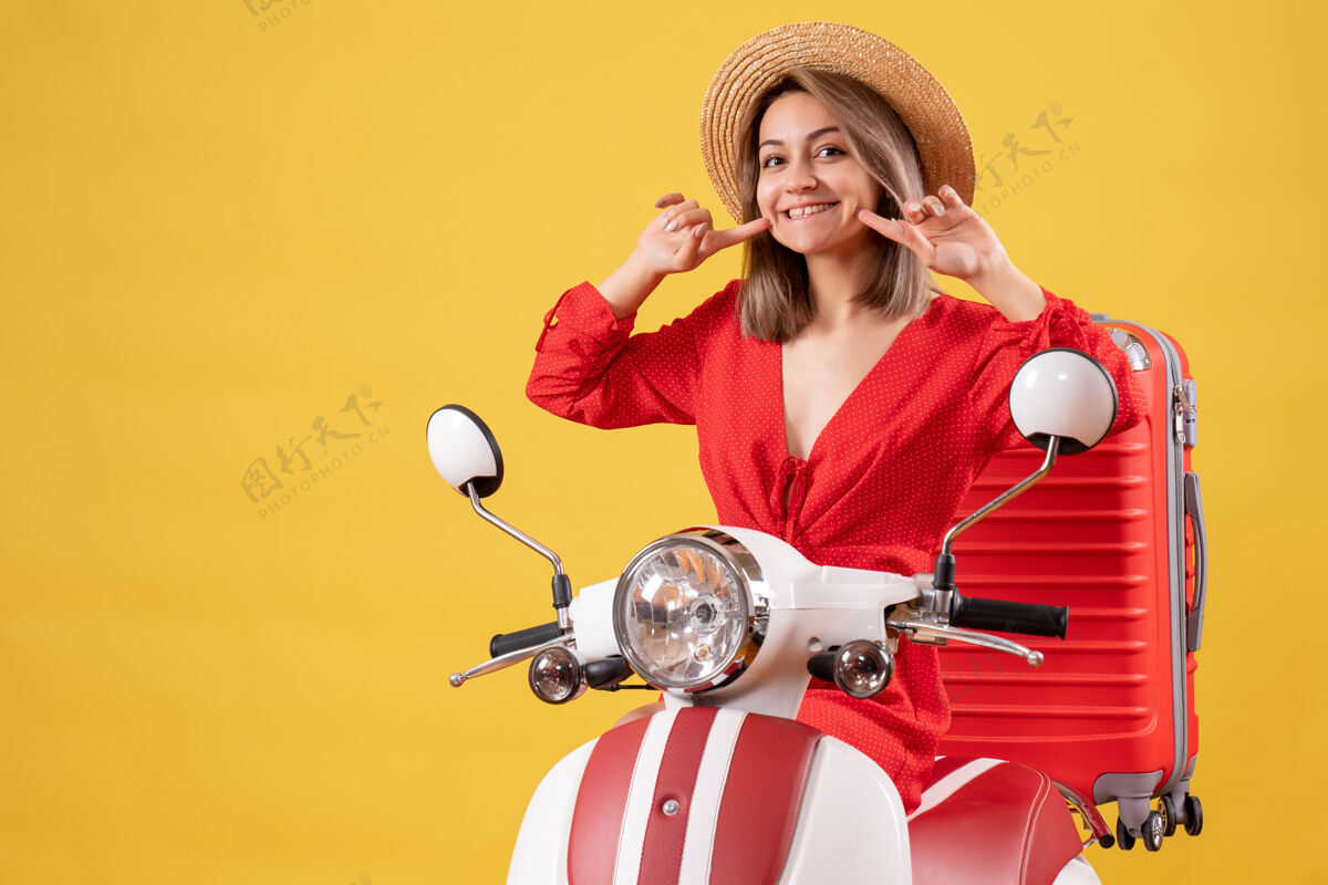 手提箱骑着轻便摩托车 带着红色手提箱的漂亮女孩微笑着时尚模型肖像