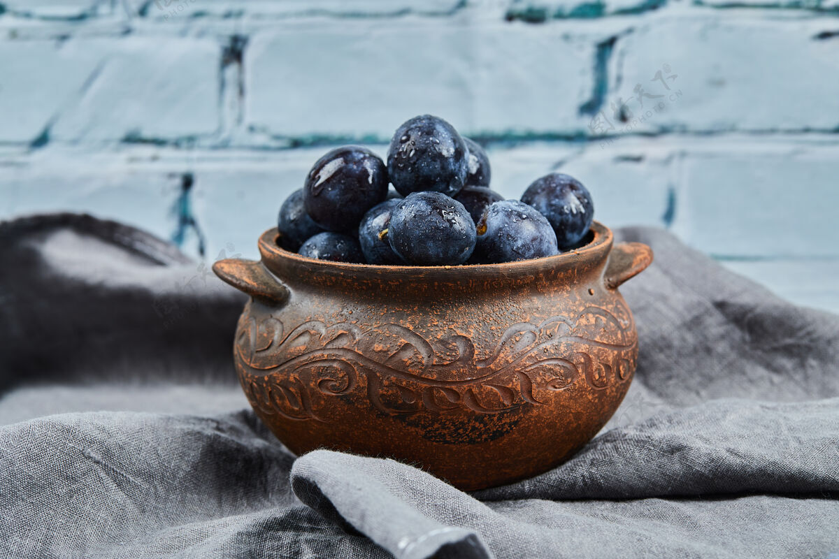桌布成熟的李子放在碗里的灰色桌布上花园美味蓝色