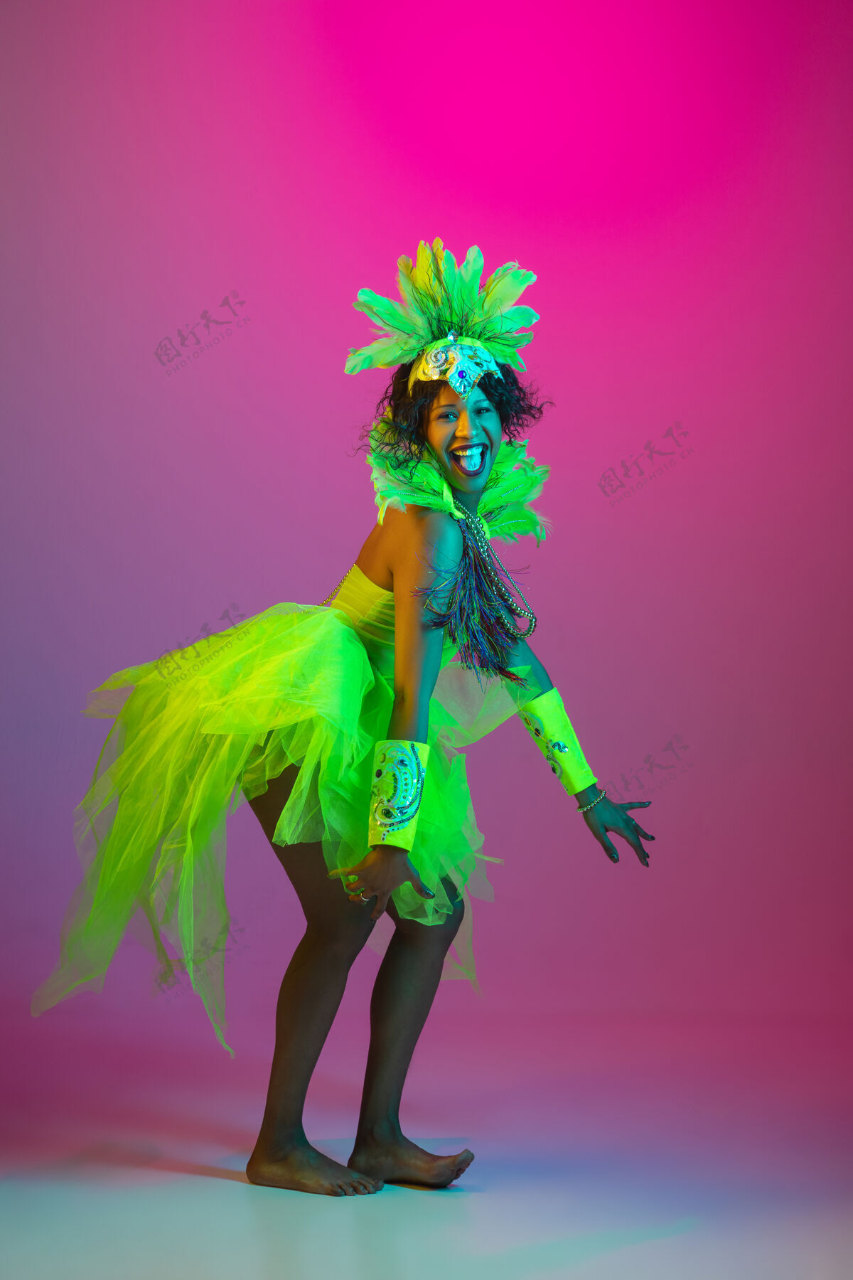 美丽美丽的年轻女子在狂欢节 时尚的化装舞会服装与羽毛跳舞的梯度墙上霓虹灯狂欢节特内里费人