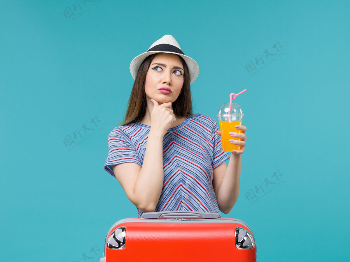 人前视图度假妇女与她的红色袋子举行她的果汁蓝色背景旅行度假女性包女性成人
