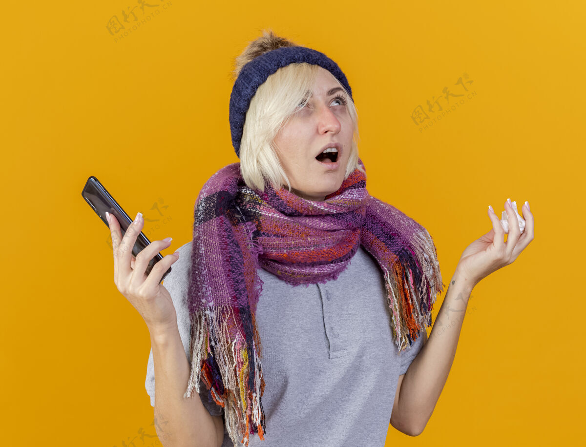 疾病年轻的金发病斯拉夫女人戴着冬天的帽子和围巾拿着电话女人围巾金发