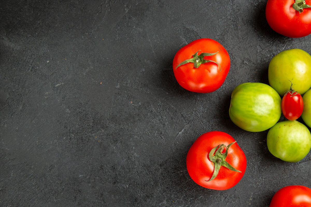 深色顶视图红色和绿色的西红柿围绕着一个樱桃西红柿在黑暗的地面与复制空间的权利蔬菜樱桃健康